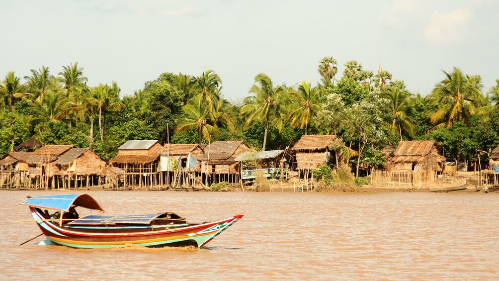 Boat passing a village along the bank of the Yangon River in Myanmar