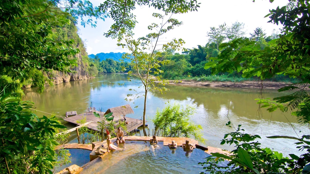 Group relaxing in riverside pools at Hintok River Camp in Thailand