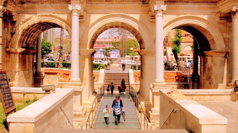 People walking under ancient archways in Antalya