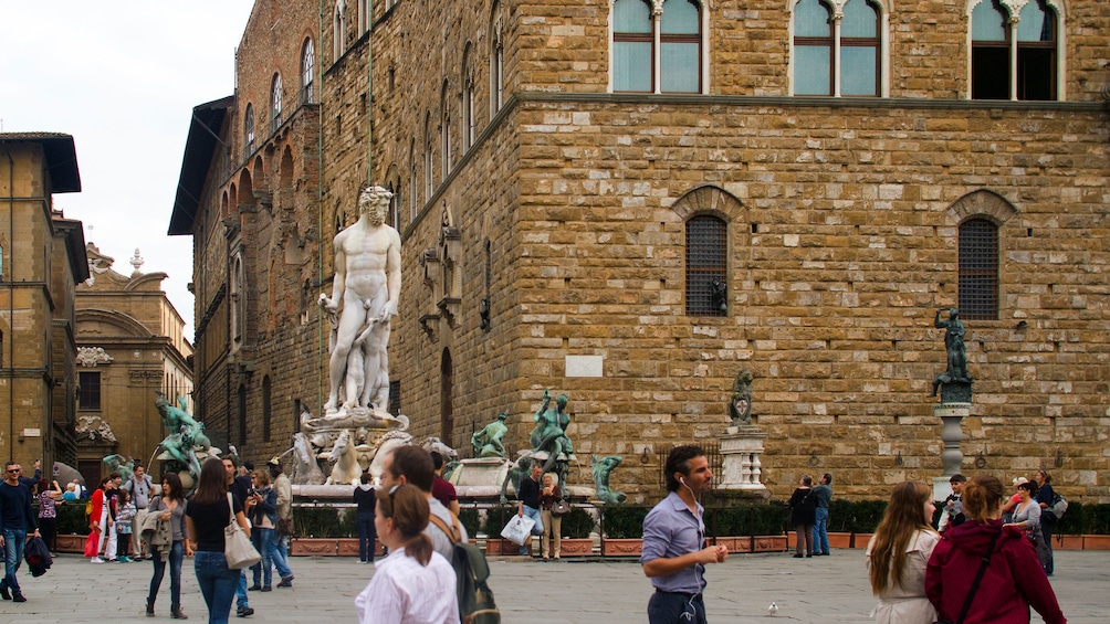 crowds walking by a marble statue in Florence