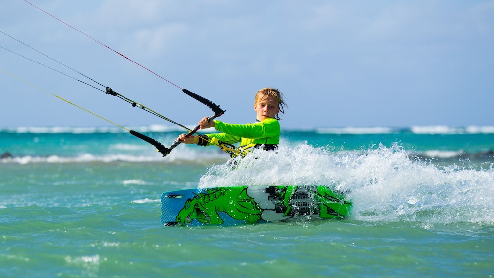 Boy kicks up some wake with his kiteboard