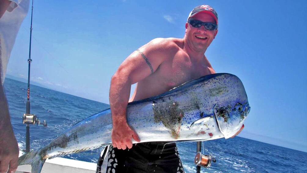 Man holding a caught dolphin fish on a boat in Puerto Vallarta