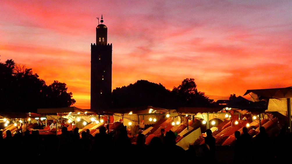 Market with silhouette of Koutoubia Mosque in the background at sunset in Marrakech