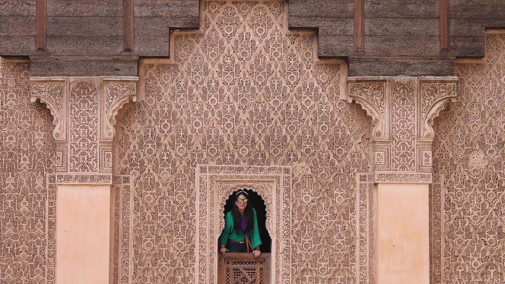 Woman peering out of her window of a Moroccan apartment in Marrakech