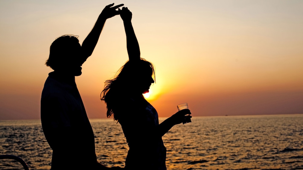 Couple dancing in the sunset aboard the Couple enjoying the Twilight Sunset Catamaran Cruise in the Turks & Caicos Islands