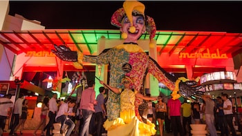 Show item 1 of 5. Man manipulates giant puppet outside club mandala