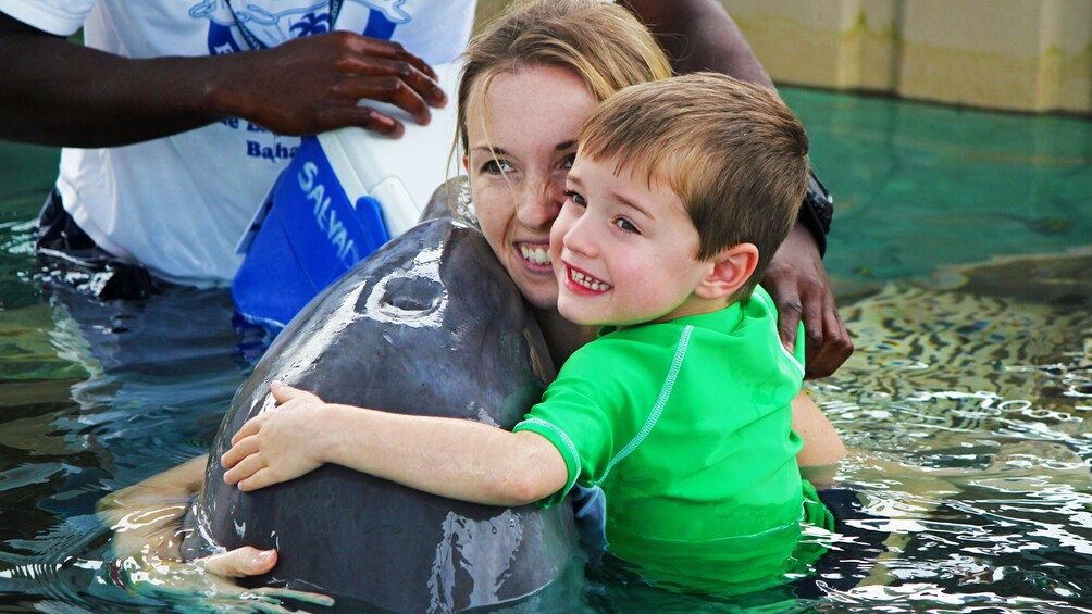 Boy and girl hugging dolphin in Bahamas