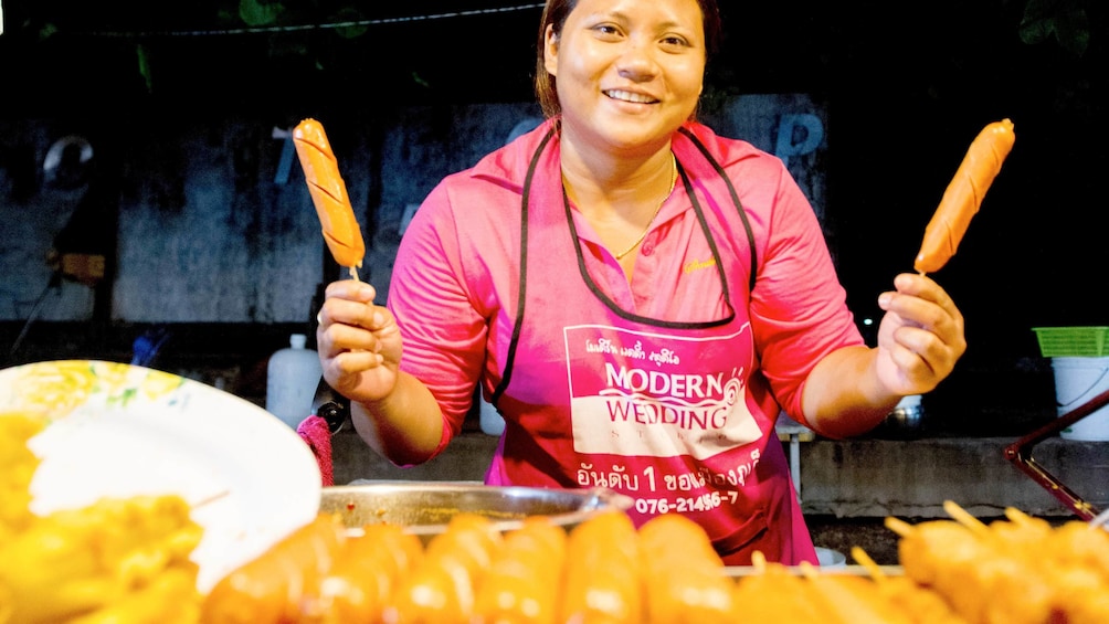woman preparing hotdogs her food stand in Thailand