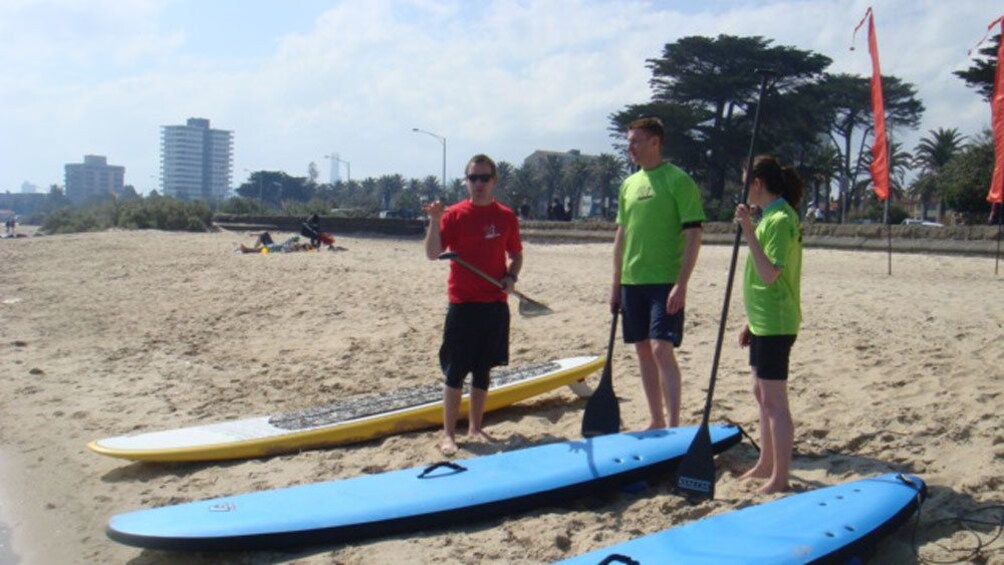 Instructor and two students stand on beach