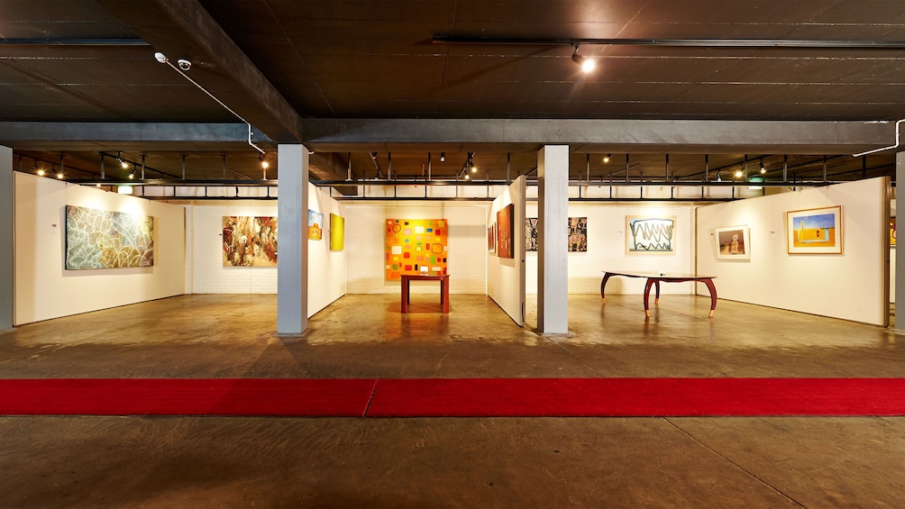 Wide view of lit up art gallery with smooth concrete flooring.