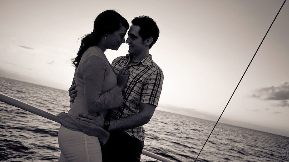 Couple embracing on sail boat at sunset.
