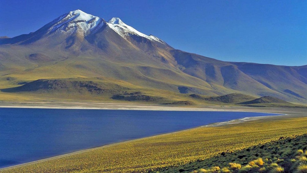 Lake with snow covered mountain peak in background in San Pedro de Atacama