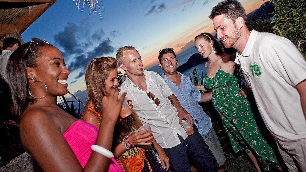 Show item 4 of 7. Partygoers enjoying party refreshments at sunset in Antigua