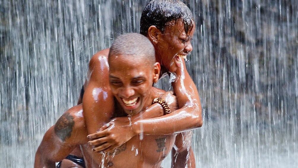 couple enjoying the water splashing down the waterfall in Saint Lucia
