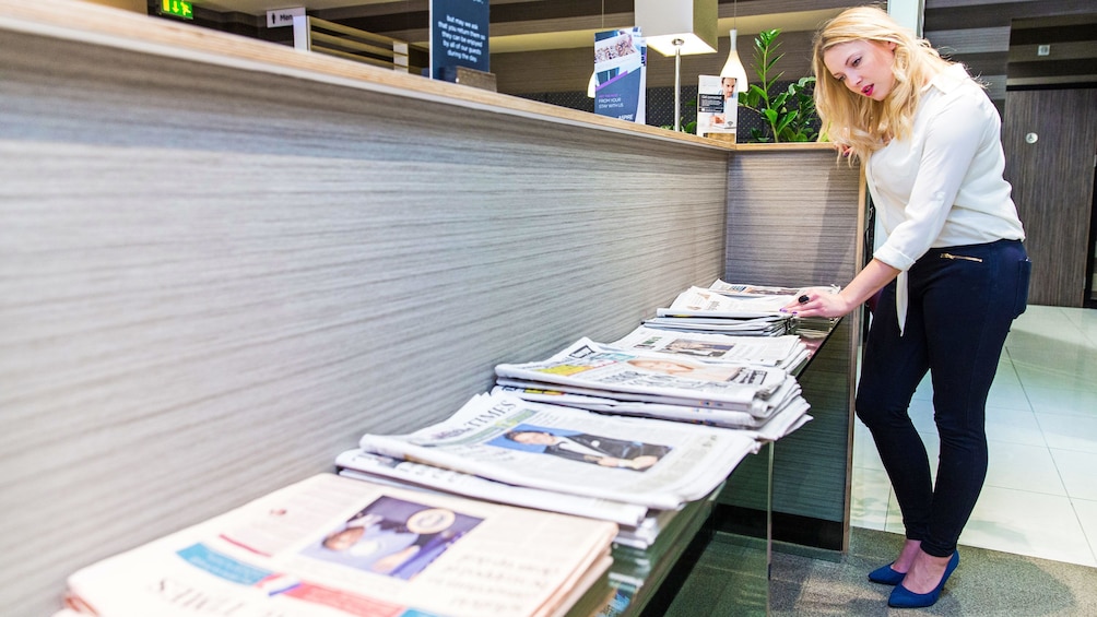 woman sifting through papers on the news stand at the airport lounge