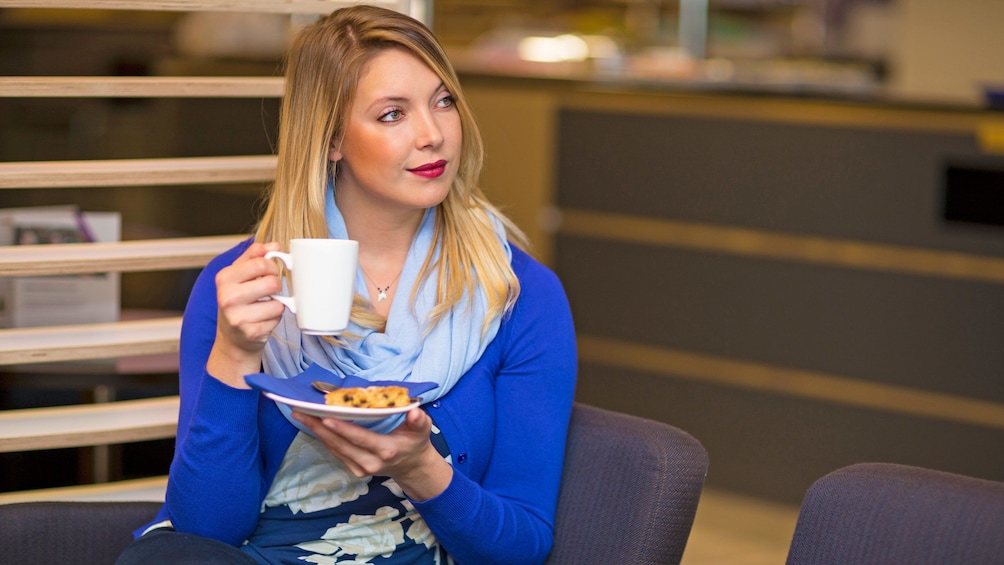 woman relaxing with a cup of coffee at the Aspire airport lounge