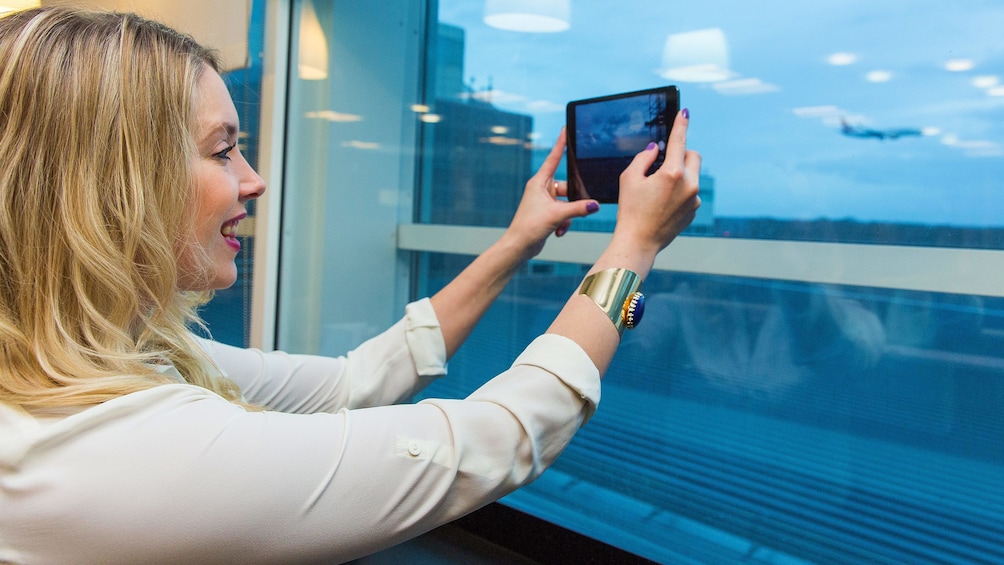 Öppna foto 5 av 5. woman taking a photo with her phone inside the Aspire airport Lounge