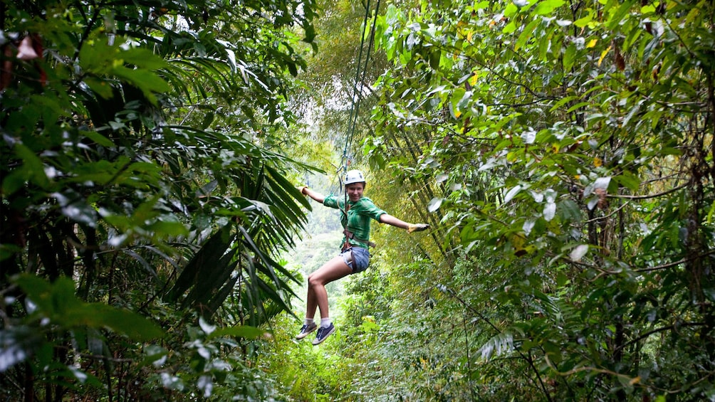 ziplining woman extending out arms for balance in Saint Lucia
