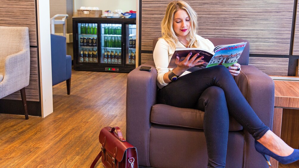 Show item 4 of 5. woman reading magazine at the airport lounge