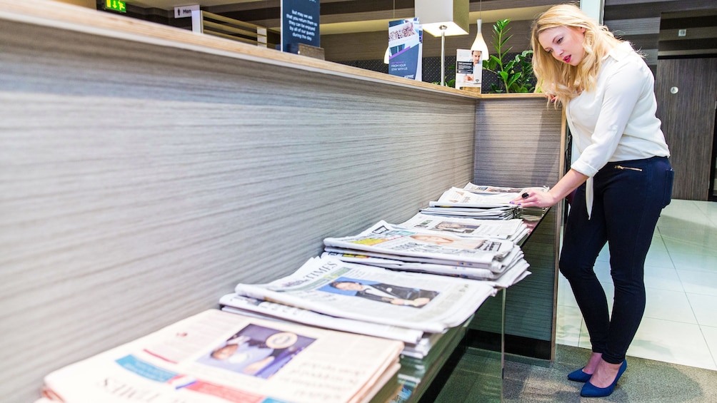 Show item 3 of 5. woman sifting through papers at the new stand in the airport lounge