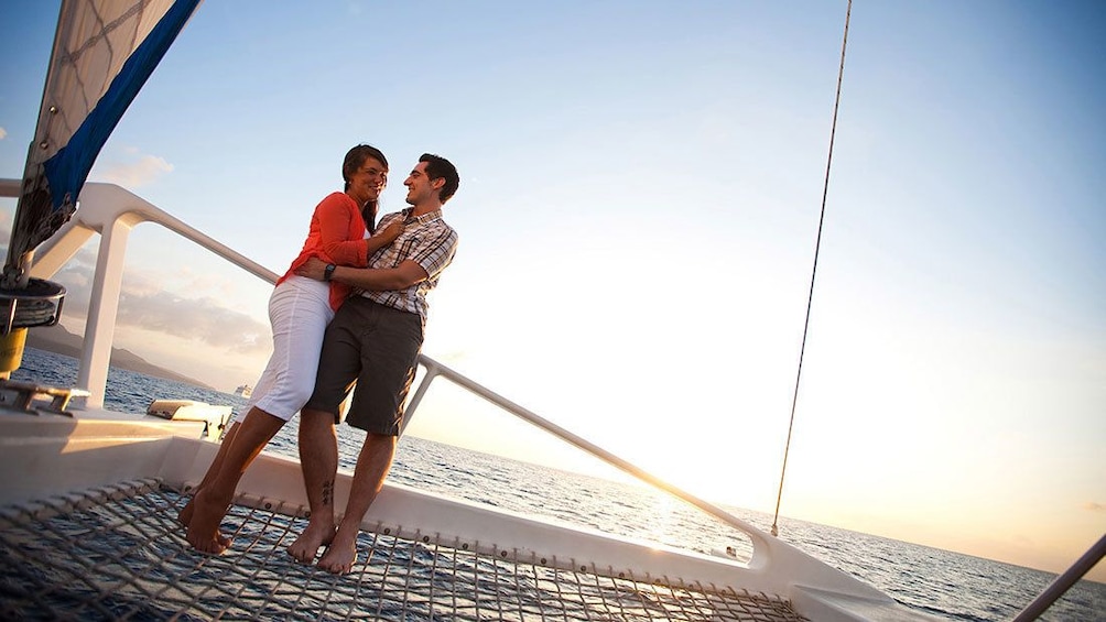 Couple embracing on sailboat by the shore.