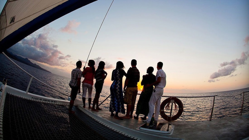 Group of people on sailboat watching the sunset.