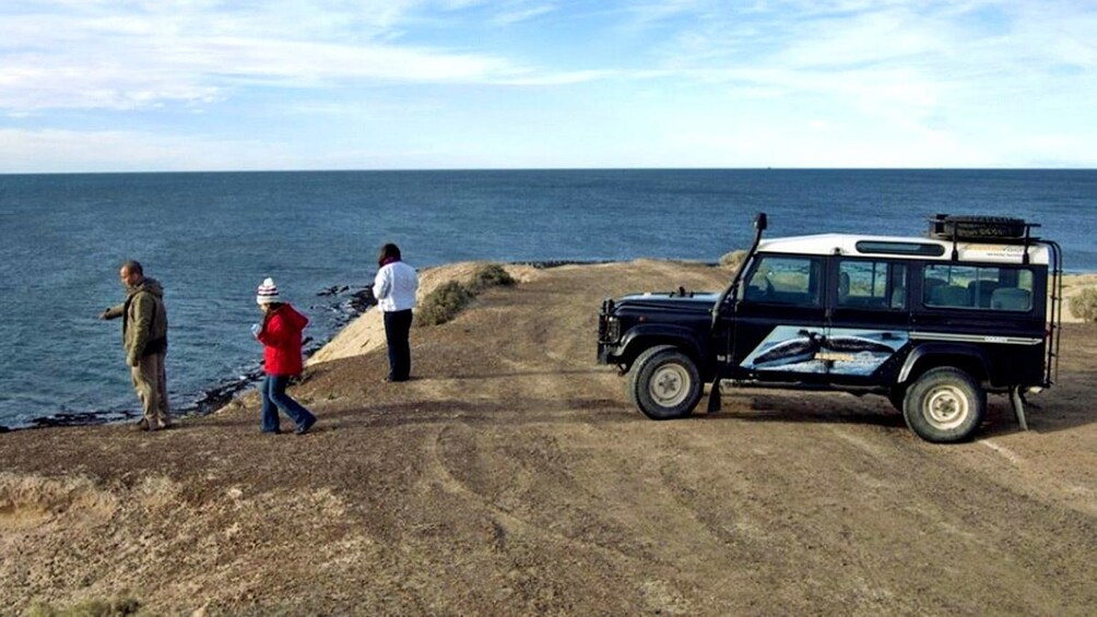 Tourists near a parked jeep along the coast in Argentina