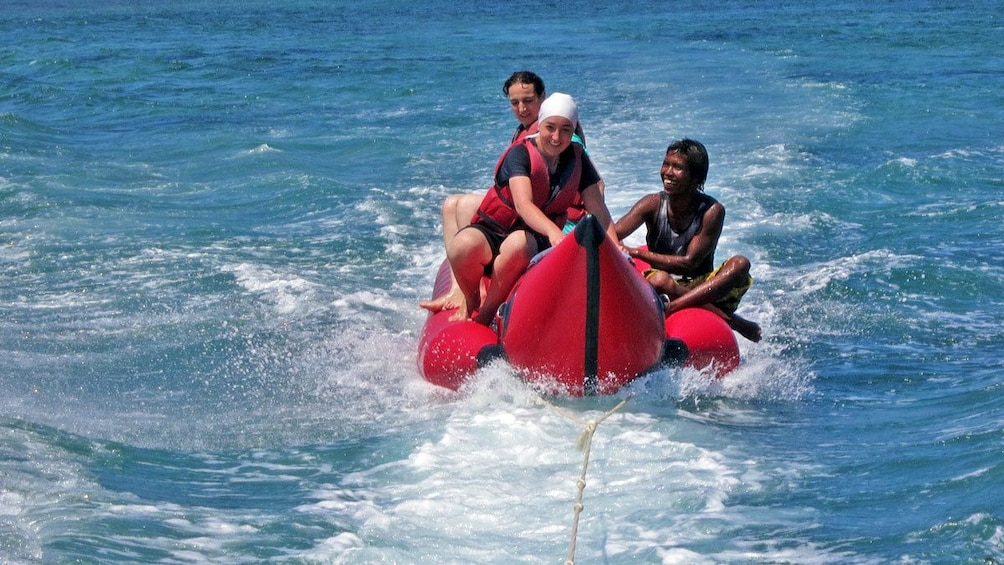 Show item 3 of 5. group hanging onto an inflatable raft pulled by a boat in Bali