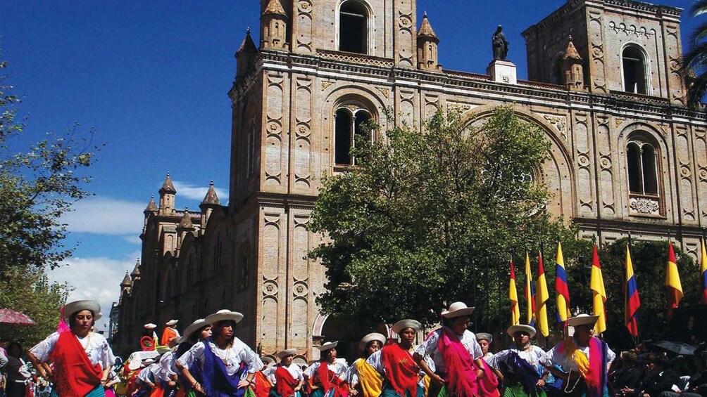 Costumed dancers performing in front of a gothic-style cathedral in Cuenca