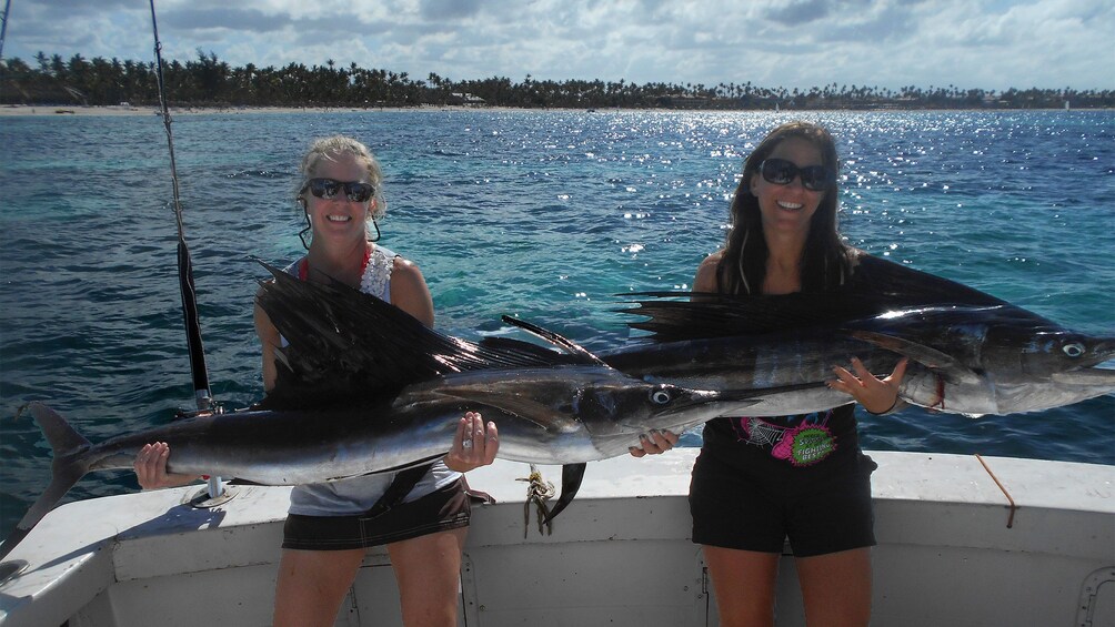 Pair of women holding up freshly caught sailfish on a boat in Punta Cana