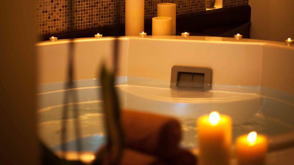 View of bathtub in treatment room surrounded by lit candles.