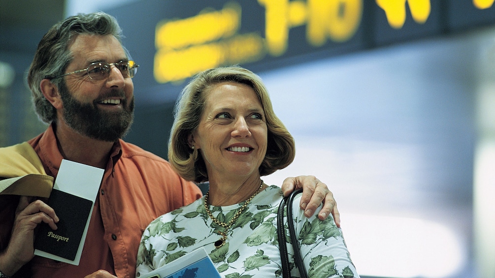 Couple smiling while holding their passports in the airport in the British Virgin Islands 