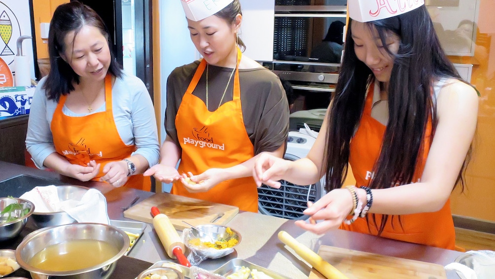 Close view of three ladies making cultural dishes in Singapore 