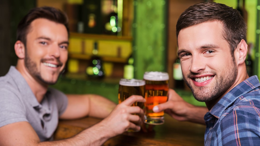Show item 2 of 5. Couple of guys toasting pints of beer in Houston