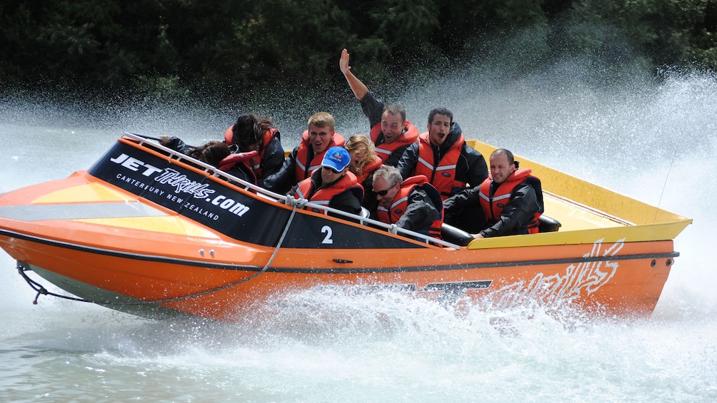 Jet boat full of people cuts through the water with large wake