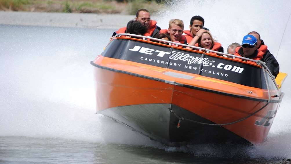 Jet boat full of people cruises through the water