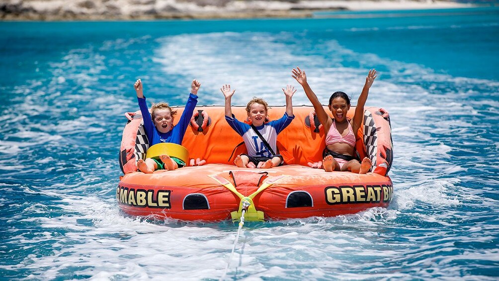 Kids on the floating raft being pulled by the boat on the private charter tour in the Turks and Caicos