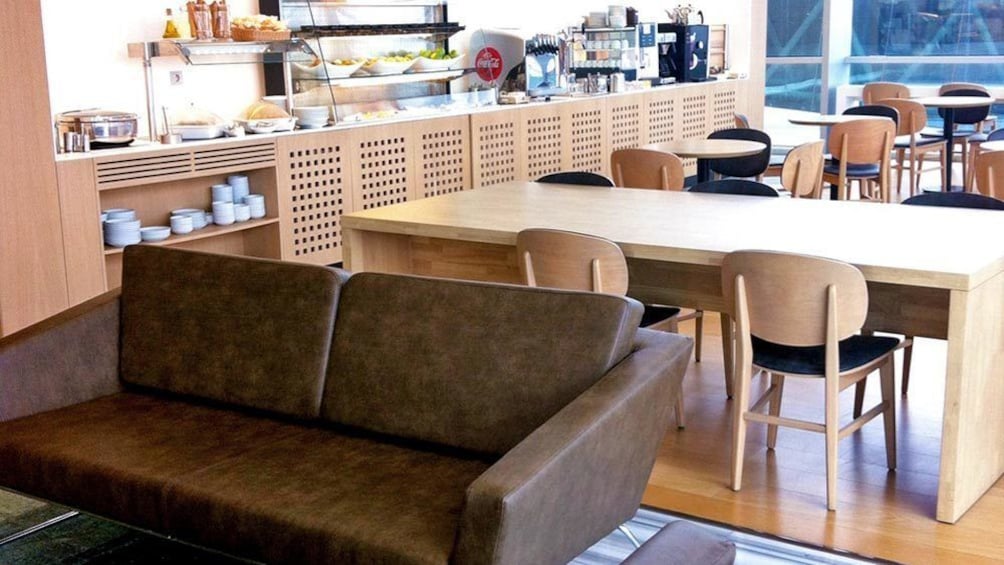 A leather couch and tables with chairs at the Izmir International Comfort Lounge