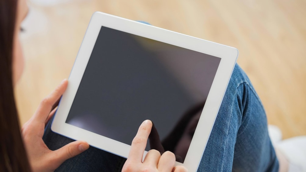 A woman pointing at a tablet that is off