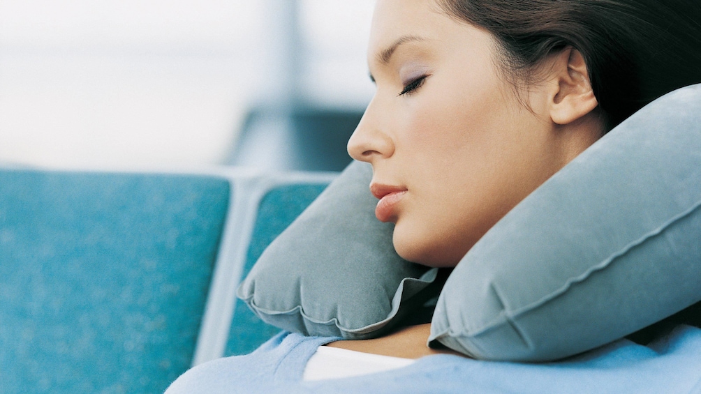A woman falling asleep with an inflatable neck rest