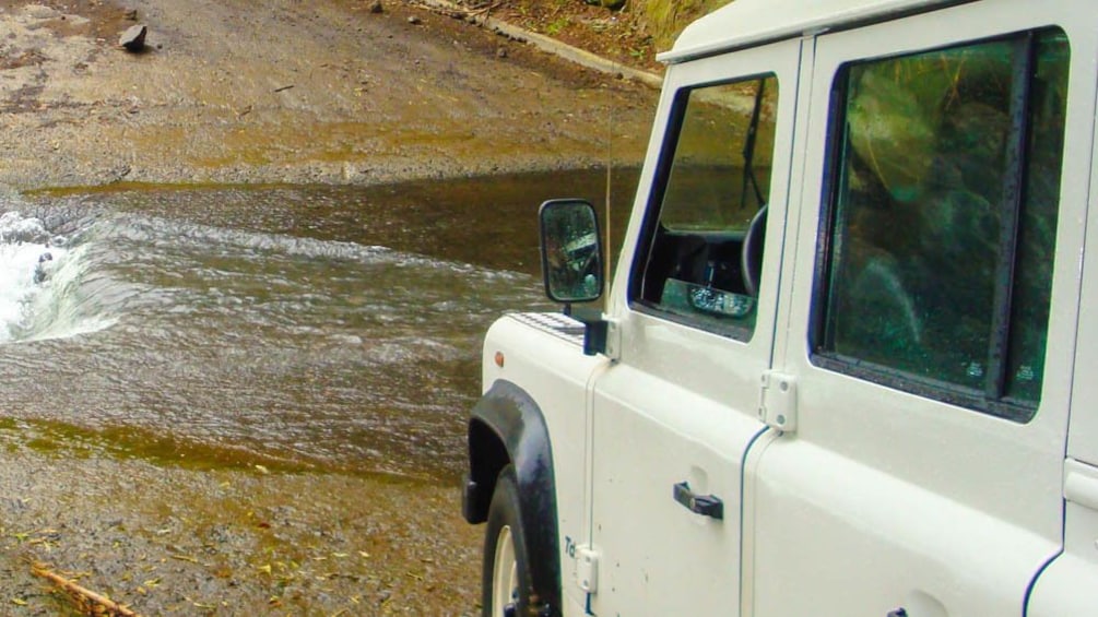 Close up of Jeep overlooking stream of water.