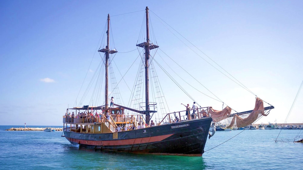 A pirate ship anchored with sails down