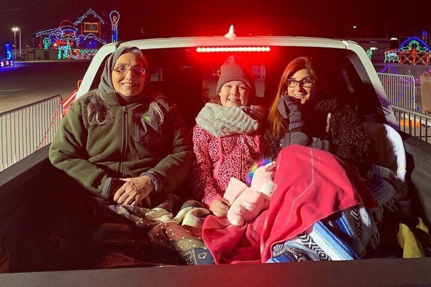 Holiday lovers getting ready to ride through the lights in their truck bed. 