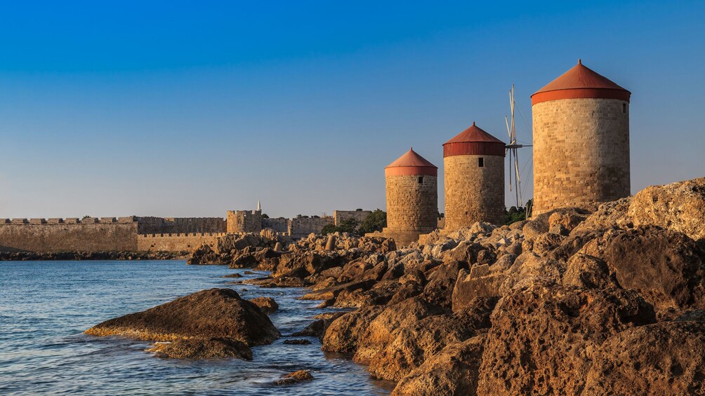 Three stone structures overlook rocky Grecian shore