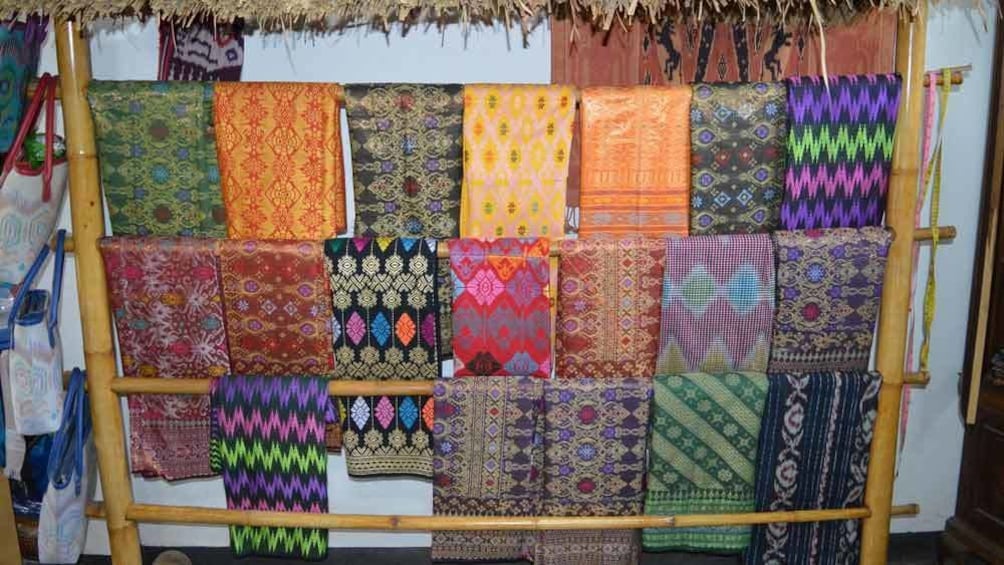 Show item 1 of 10. Folded bolts of multi-colored fabrics on a rack