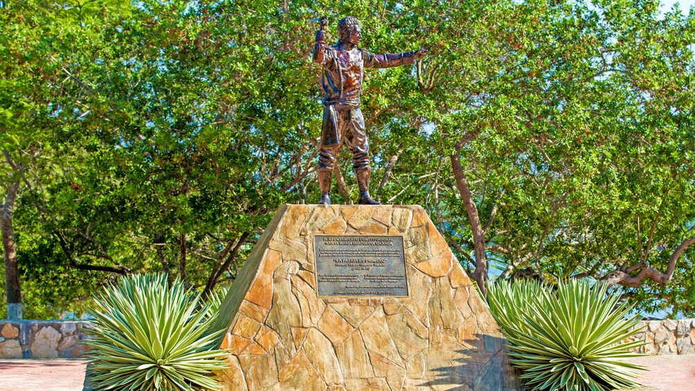 A bronze statue in Mexico with a Jungle in the background