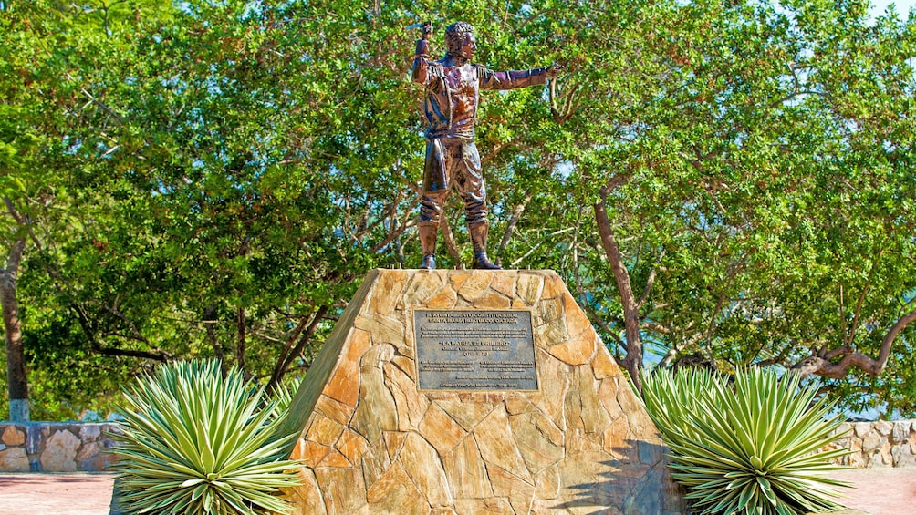 A bronze statue in Mexico with a Jungle in the background