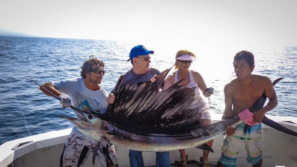 Tourist group posing with large exotic fish that has been caught.