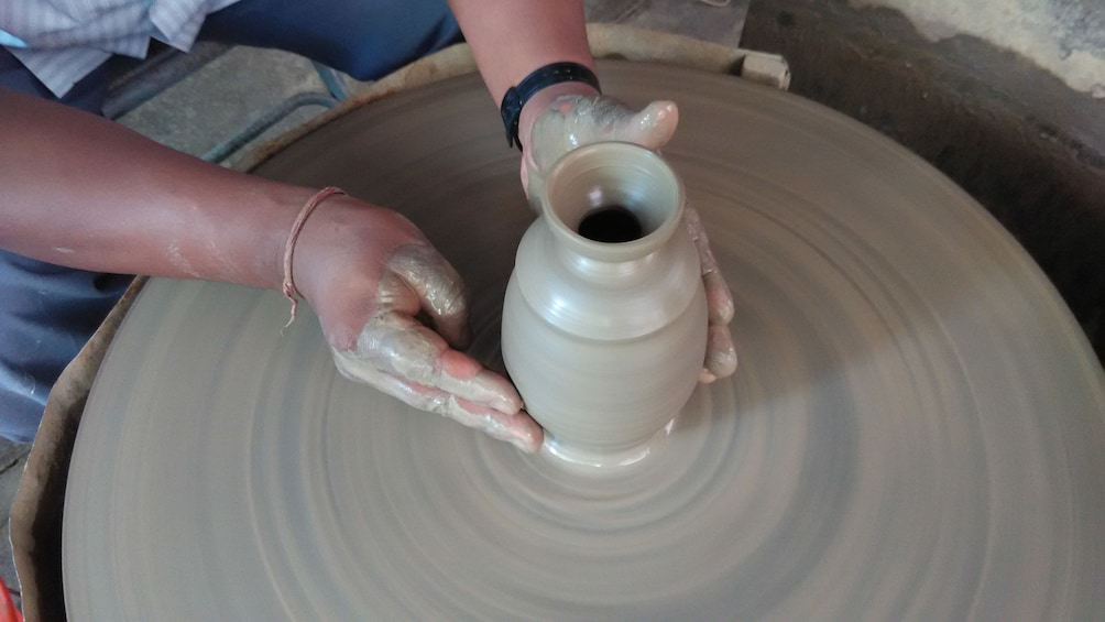 Show item 1 of 5. Medium shot of potter working on vase