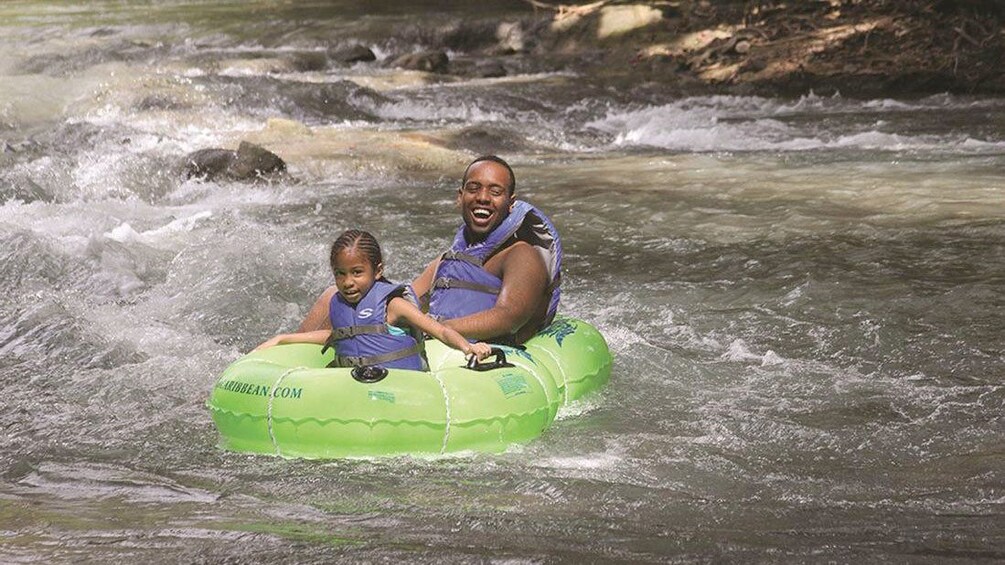 Father and daughter enjoying inner tubbing in down a river in Jamaica 